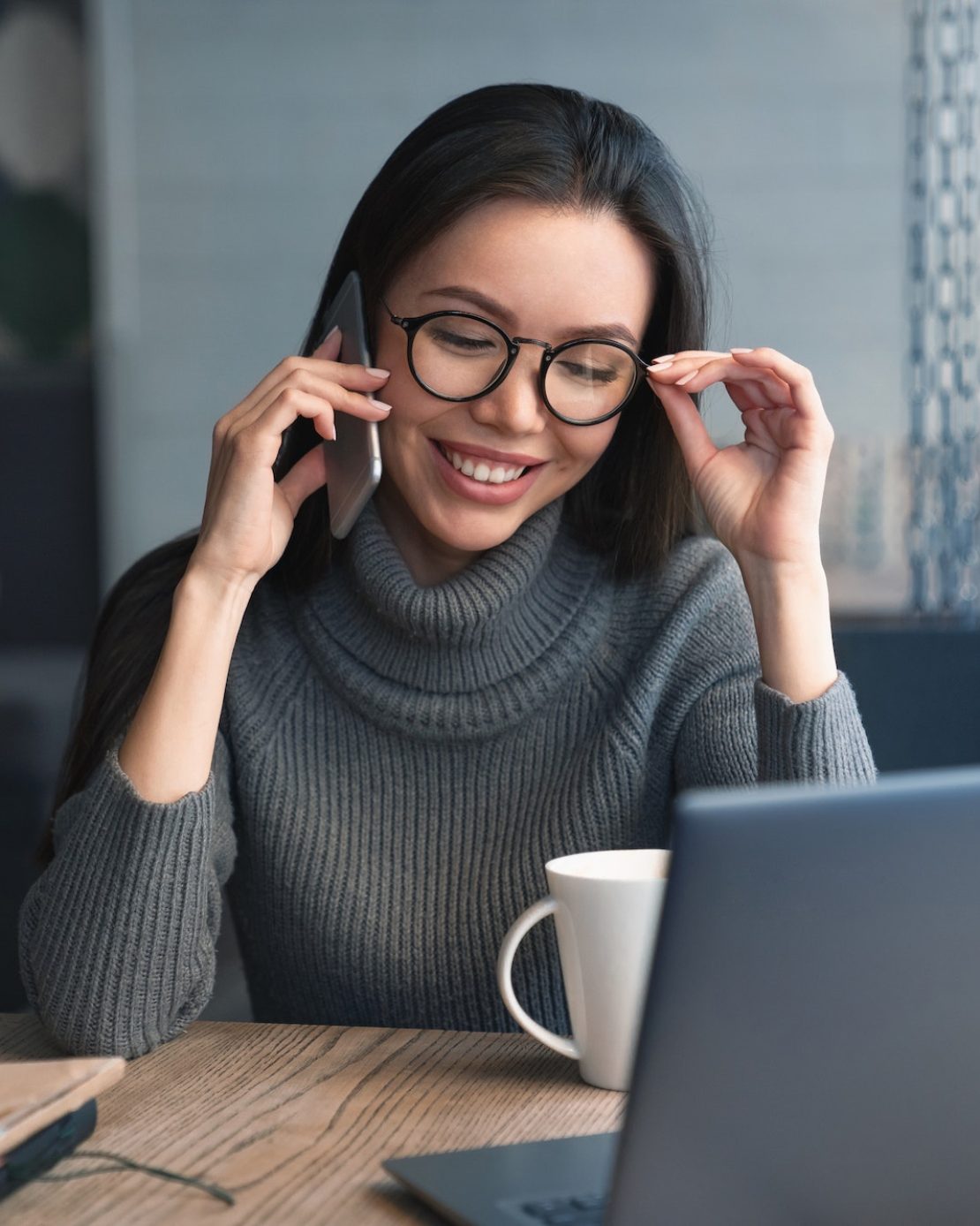 Cheerful female executive have conversation by mobile phone with client at coworking place