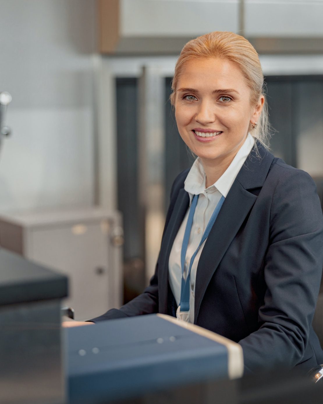 Smiling pretty female airport employee sitting at the check-in desk